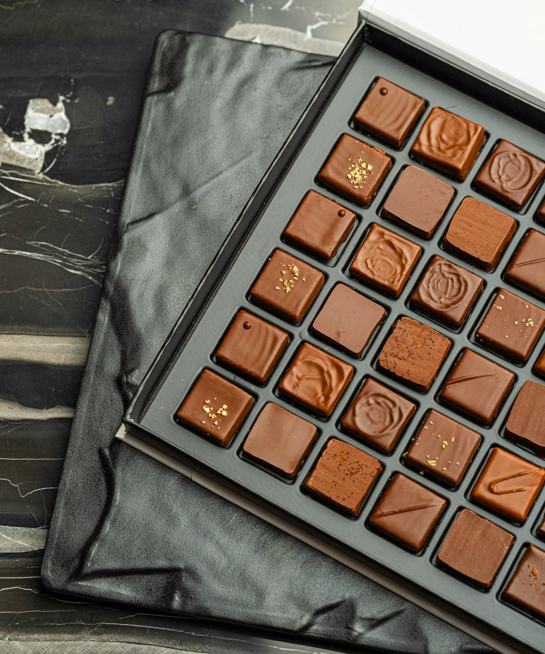 Pralinen mit Goldstaub in dunkler Schatulle